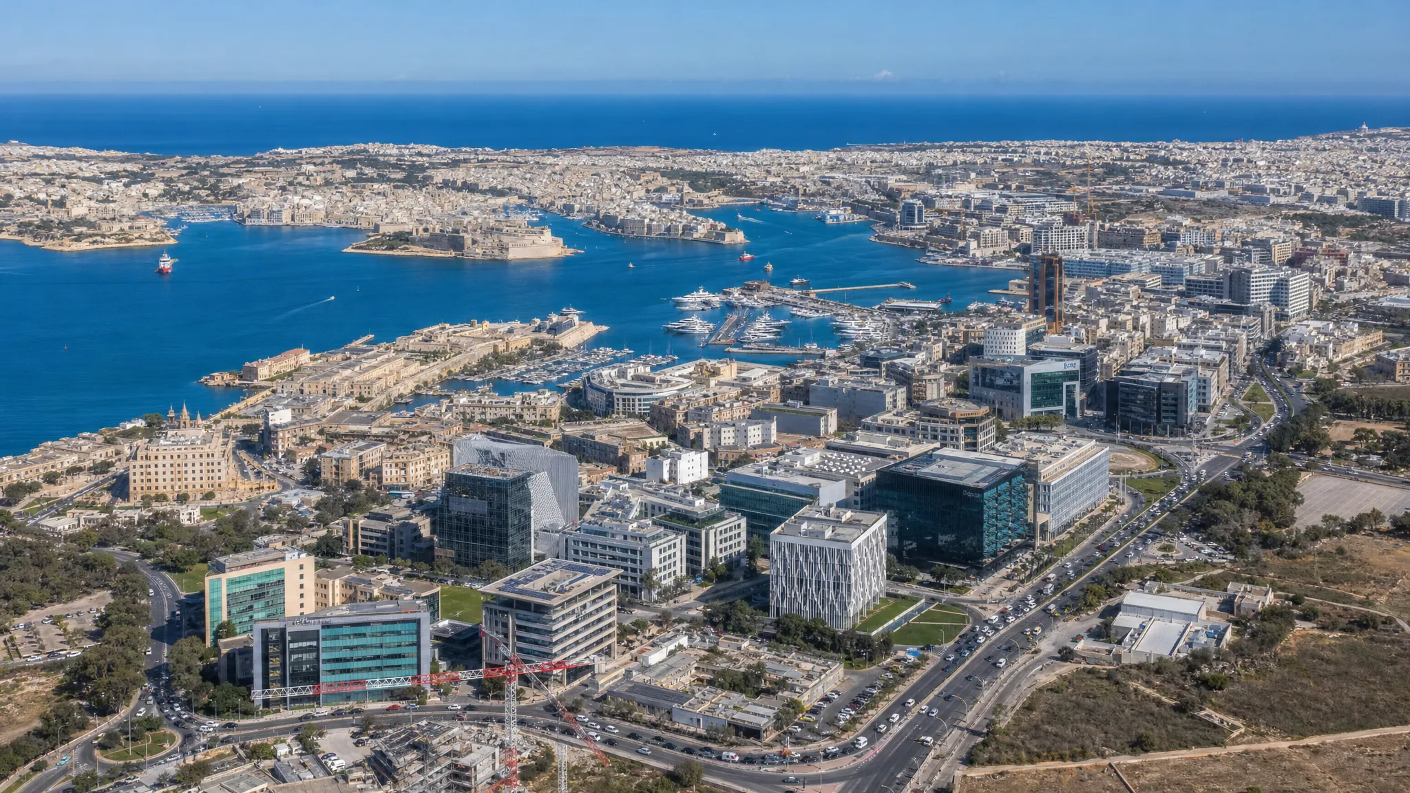A panoramic aerial view of Malta’s main business districts, showing the harbour, clusters of office buildings, inland commercial zones, busy roads and distinct areas that suit different types of companies.