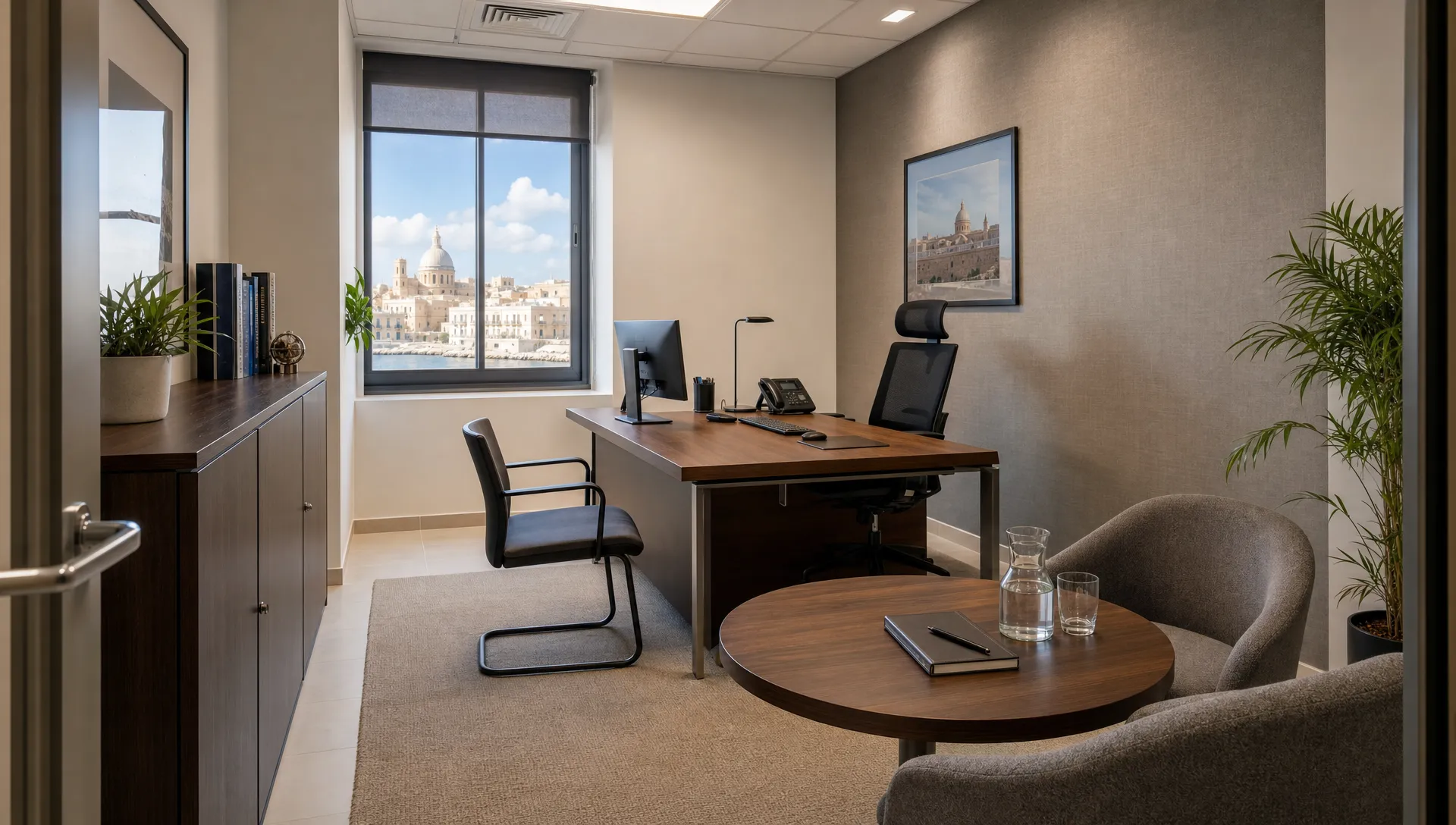 A compact private office in Malta with a desk, ergonomic chair, visitor chair, storage cabinet, natural light and a small meeting corner prepared for client conversations.